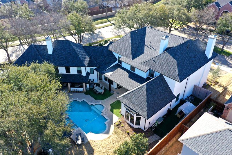 Aerial view of a two-story home with a new charcoal architectural shingle roof by Benchmark Roofing and Construction