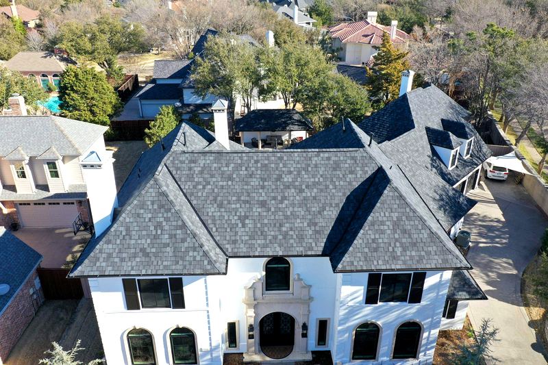 Aerial view of a French-style home with a new charcoal architectural shingle roof by Benchmark Roofing