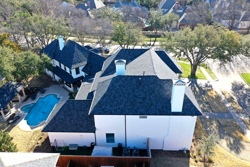 Aerial view of a luxury two-story home with a dark charcoal architectural shingle roof by Benchmark Roofing