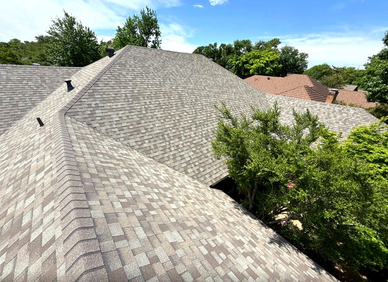 New tan architectural asphalt shingle roof with multiple hips by Benchmark Roofing and Construction